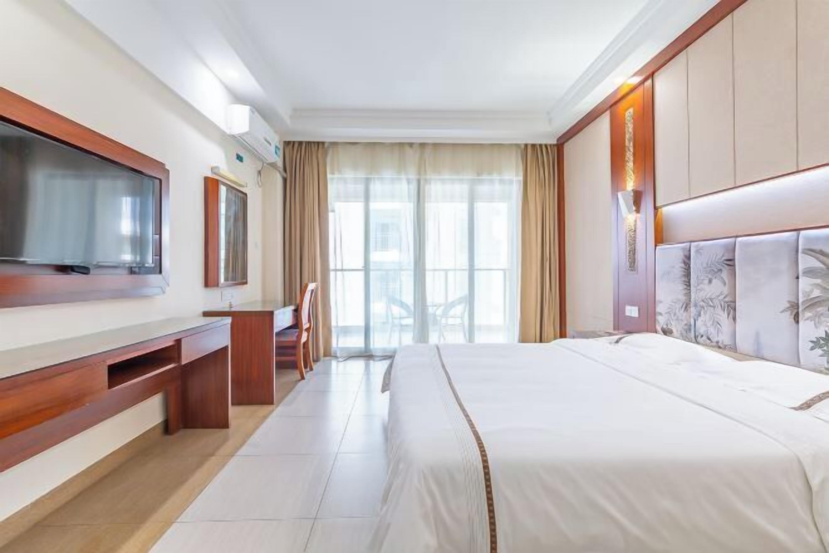 Habitación de hotel con una cama grande, un televisor montado en la pared, un escritorio y una silla.
