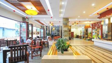 A spacious restaurant with wooden furniture, a central planter with greenery, and a modern ceiling design.