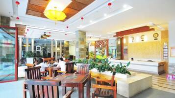 A restaurant with wooden furniture, a reception desk, and a ceiling fan.