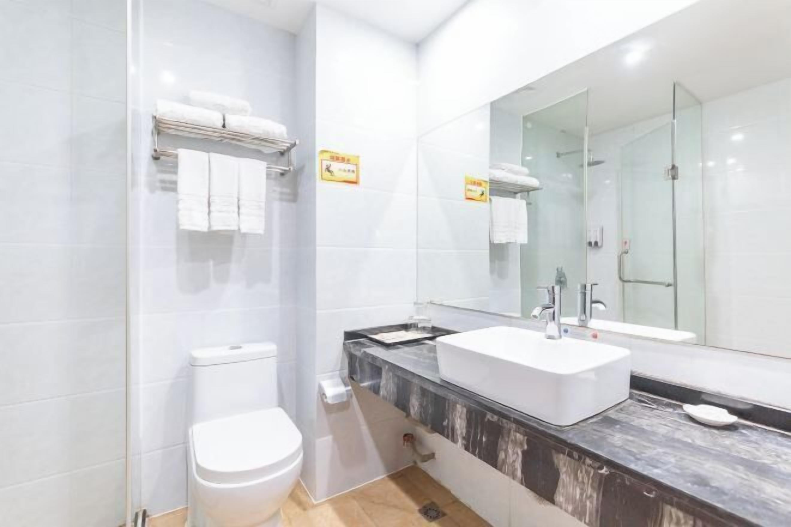 A modern bathroom with a white toilet, a large mirror, and a marble countertop.
