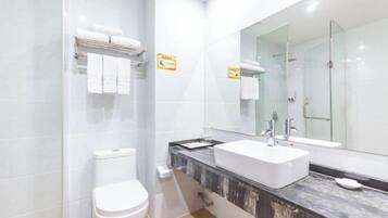 A modern bathroom with a white toilet, a large mirror, and a marble countertop.