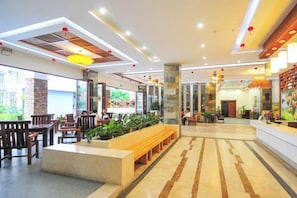 A spacious lobby with a reception desk, seating area, and large windows.
