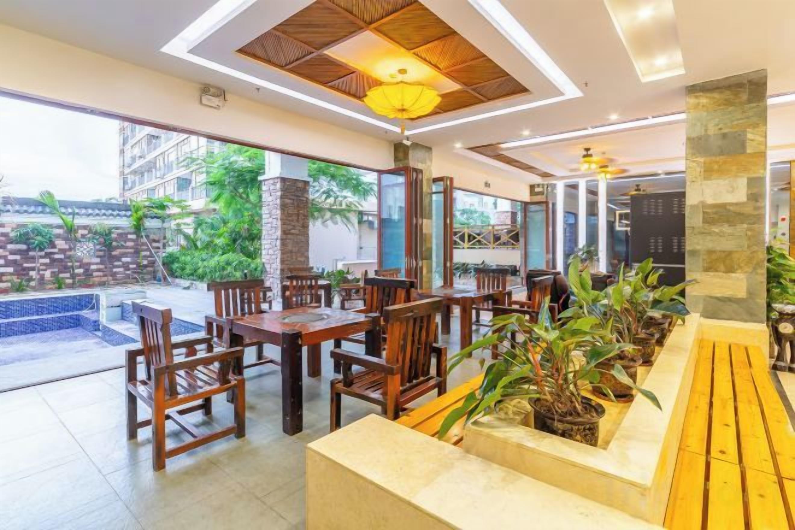 A restaurant with wooden tables and chairs, a stone column, and a view of the outdoor area.