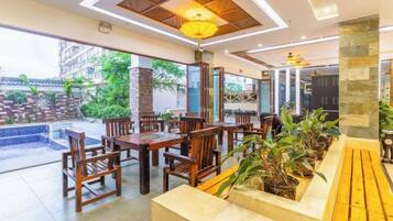 A restaurant with wooden tables and chairs, a stone column, and a view of the outdoor area.