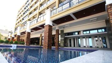 Un hotel de varios pisos con una piscina al frente.