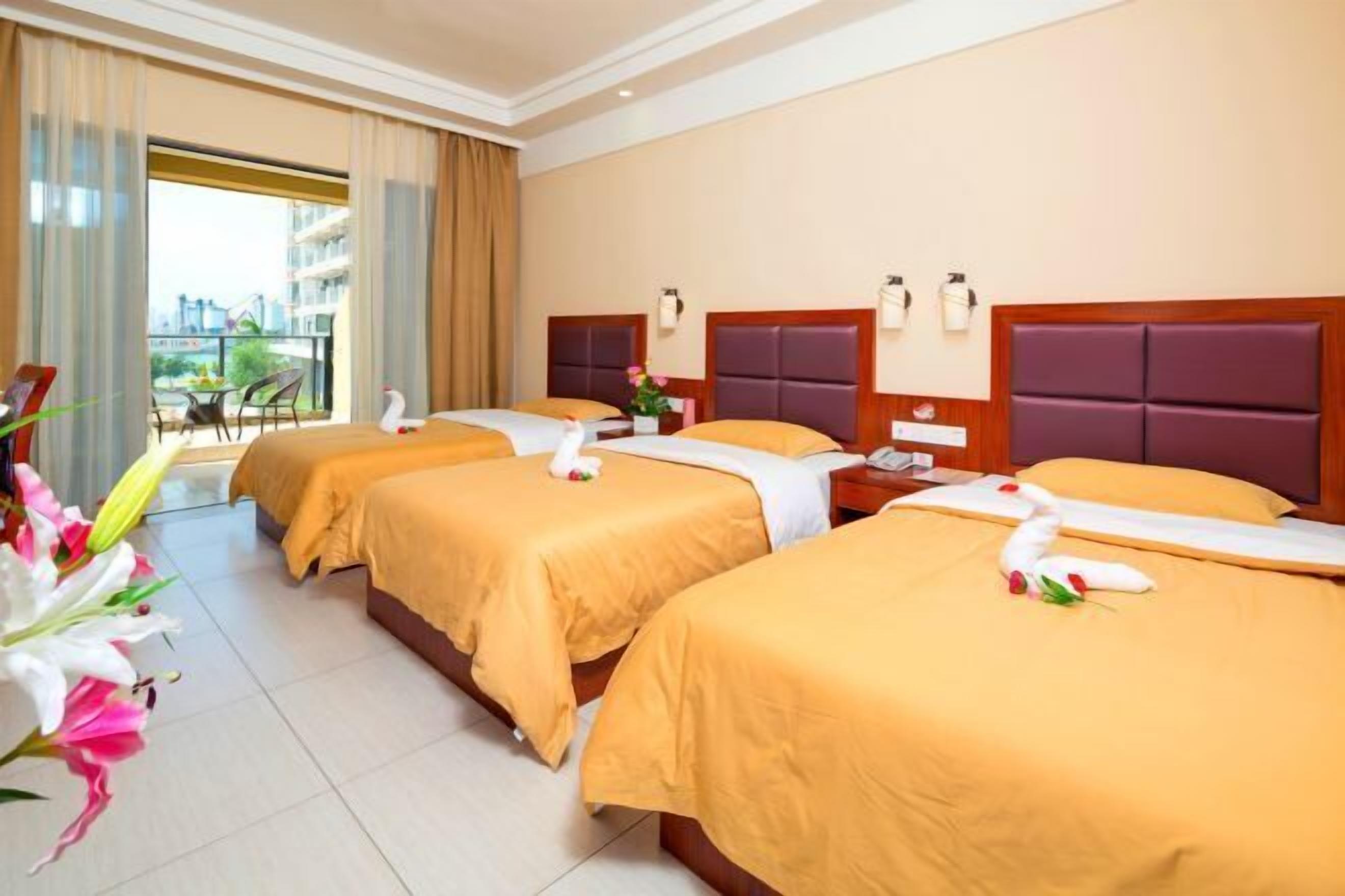 A hotel room with three beds, a balcony, and a view of the city.