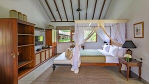 A bedroom with a canopy bed, wooden furniture, a television, and a view of greenery outside. - Taru Villas THE Long House (Bentota)