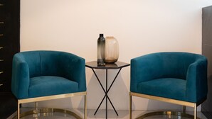 Un interior moderno con dos sillas color turquesa, una mesa de vidrio y un letrero en la pared que dice "GEMA RESTAURANTE".