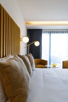 Una habitación de hotel con una cama grande, un sofá, una mesita y una lámpara.