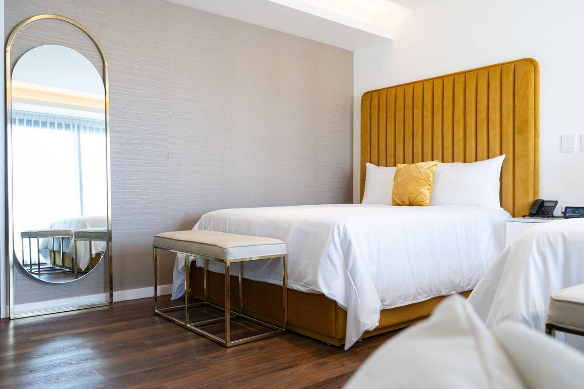 Une chambre d’hôtel avec un grand lit, une table de chevet, un miroir et une vue sur l’extérieur.