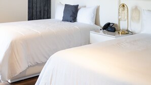 Habitación de hotel con dos camas, una mesita de noche con lámpara y un teléfono.
