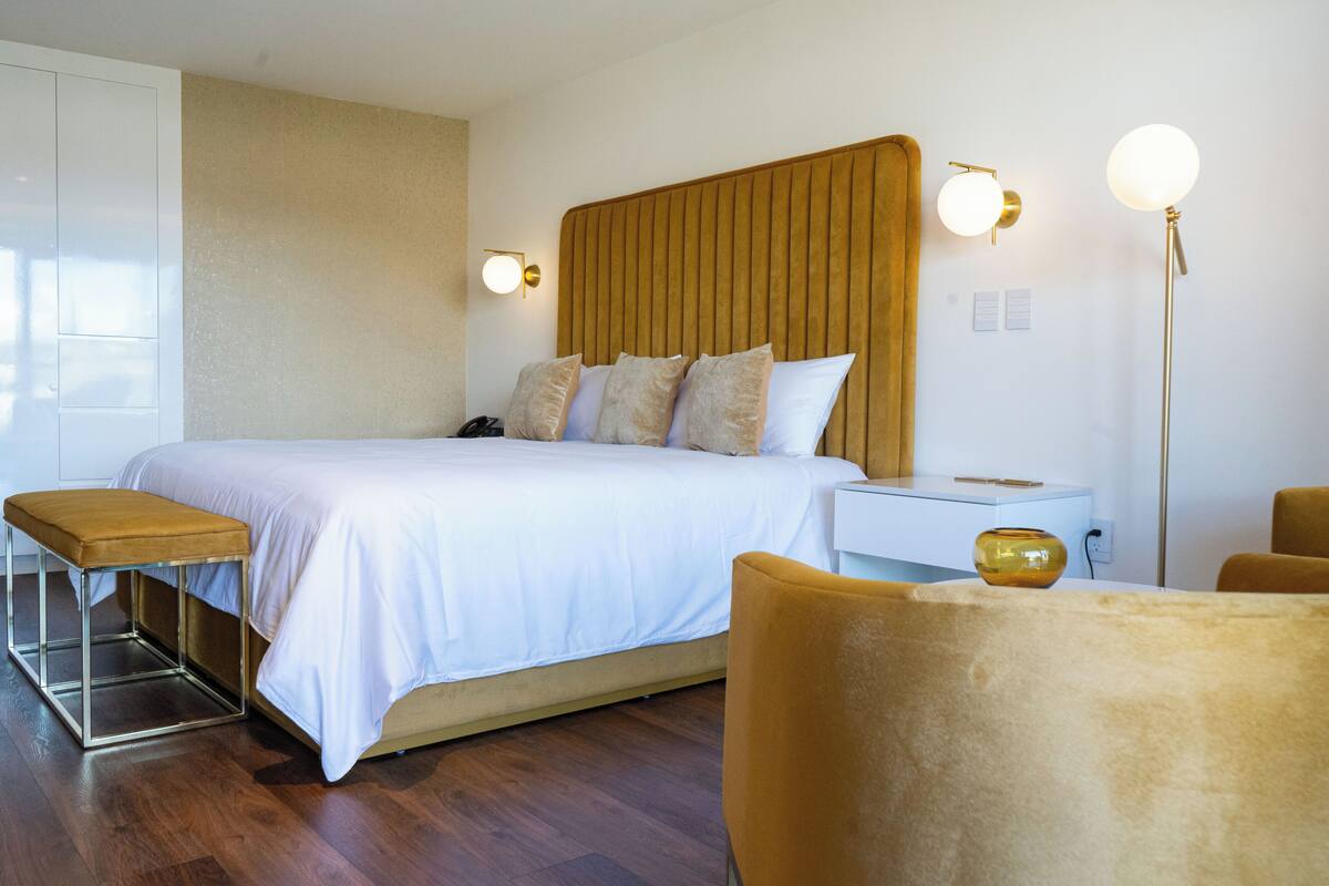 Une chambre d’hôtel moderne avec un grand lit, une table de chevet et une lampe sur pied.