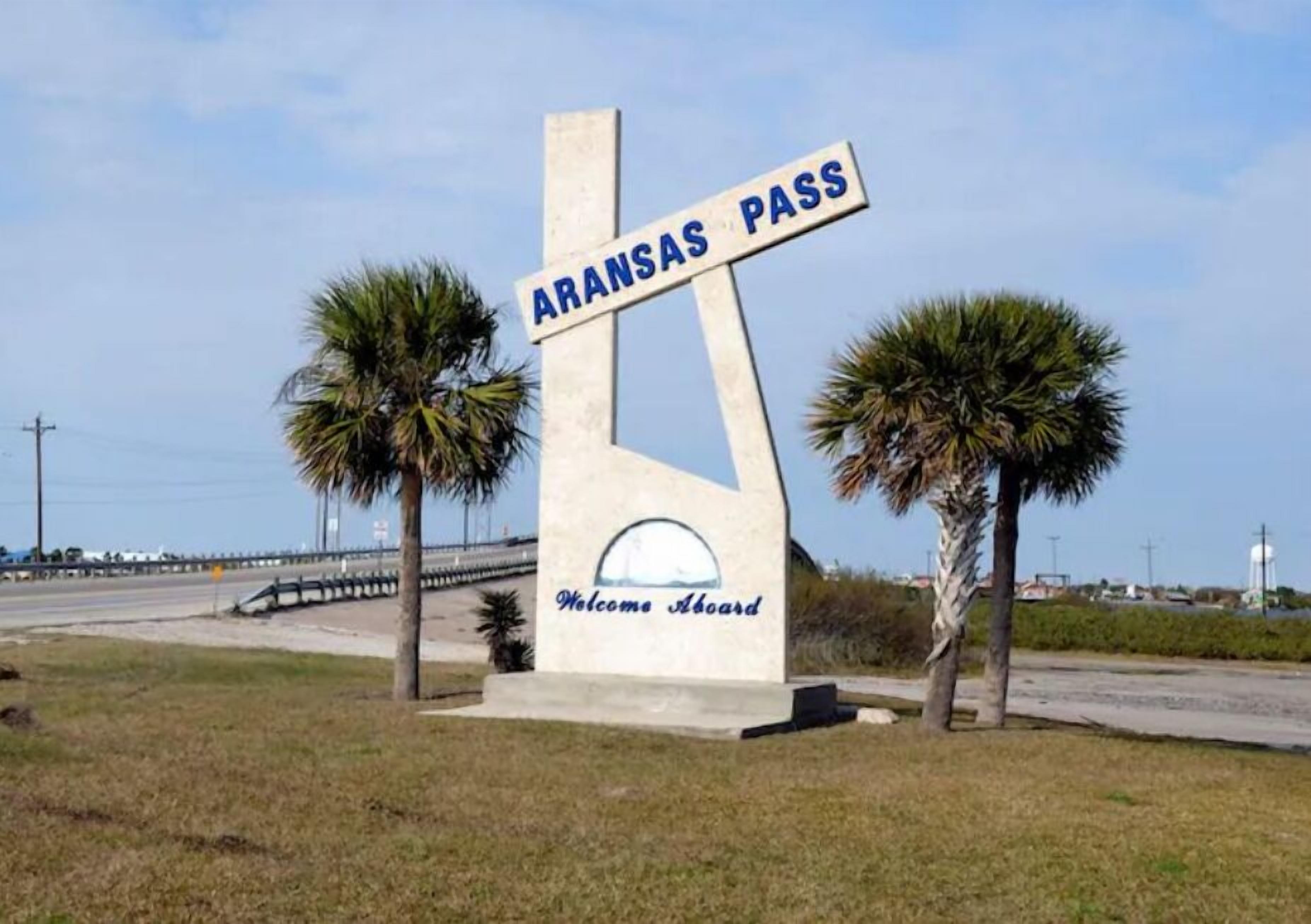 A sign with 'ARANSAS PASS' and 'Welcome Aboard' text, surrounded by palm trees.