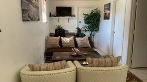 Un saló amb un sofà, dues butaques, una taula de centre, una televisió i una planta.