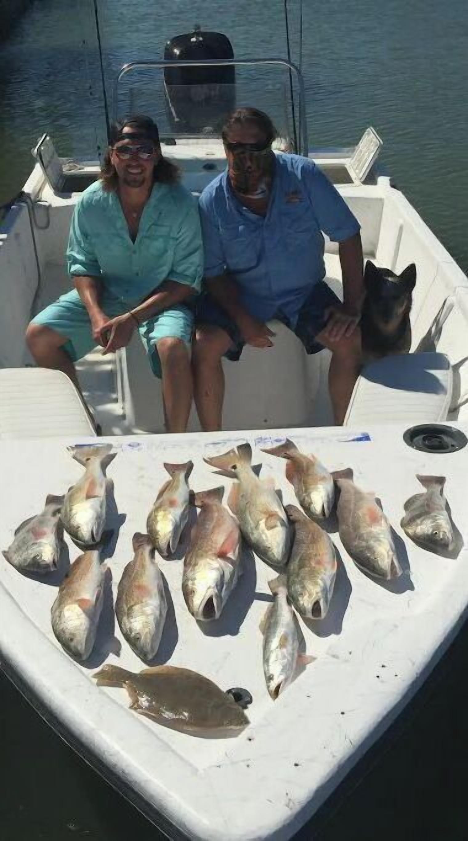 To personer i en båd med mange fisk på dækket.