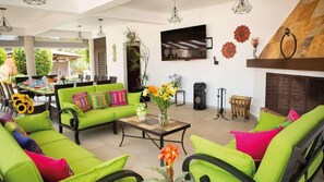 Amplia sala de estar con sofás verdes, una mesa de centro y una chimenea.