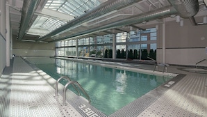 Una piscina interna con soffitti in vetro trasparente e pavimento piastrellato.