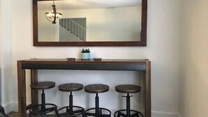 Un espace bar avec une console en bois et quatre tabourets.
