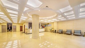 Um hall amplo com uma coluna central, balcão de recepção e área de estar.