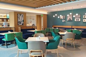 A restaurant with booths and tables, a counter with a chef, and artwork on the walls. - Dijing Wanyue Hotel (Zhuhai)