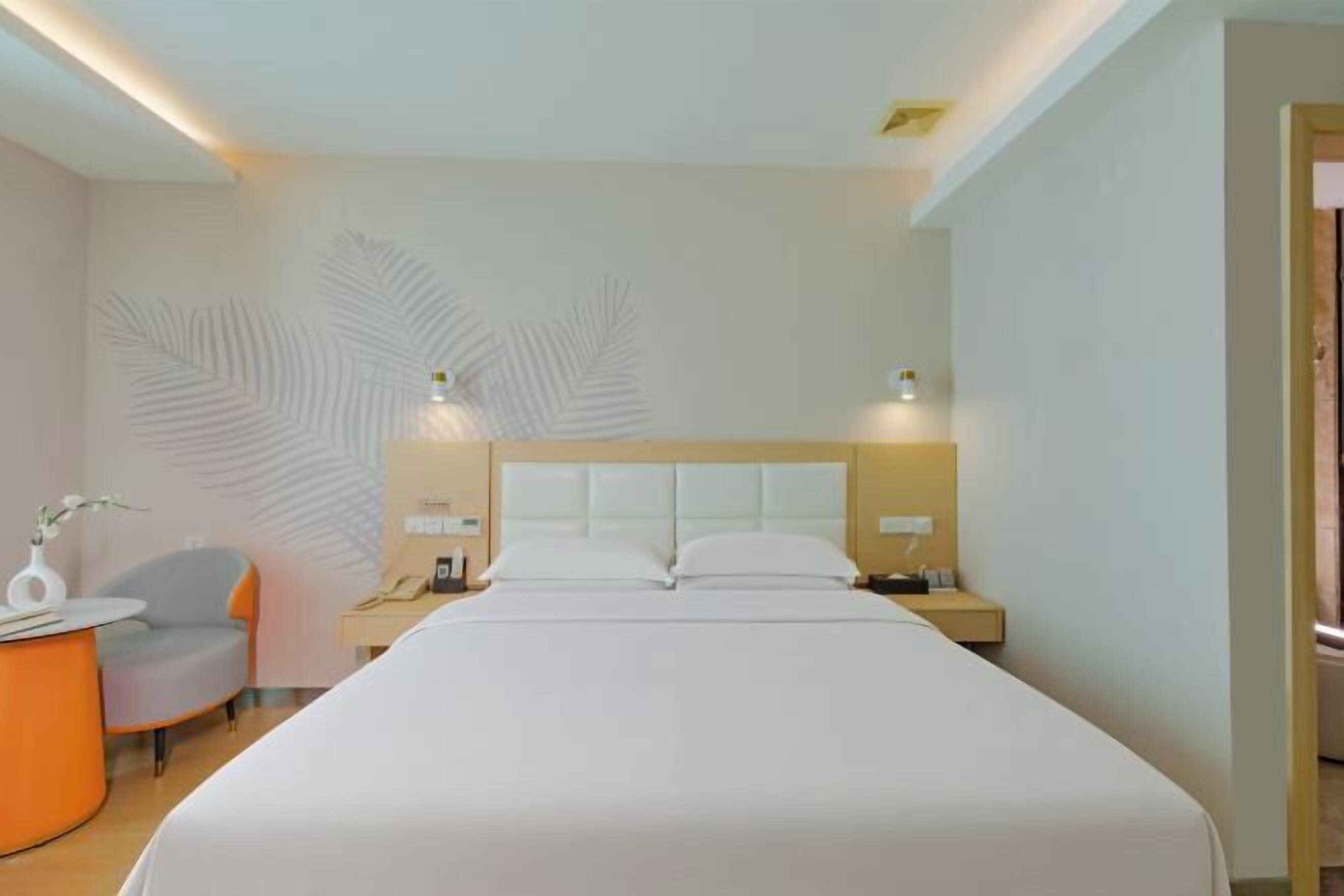 A modern hotel room with a large bed, a desk, a chair, and a decorative wall design.