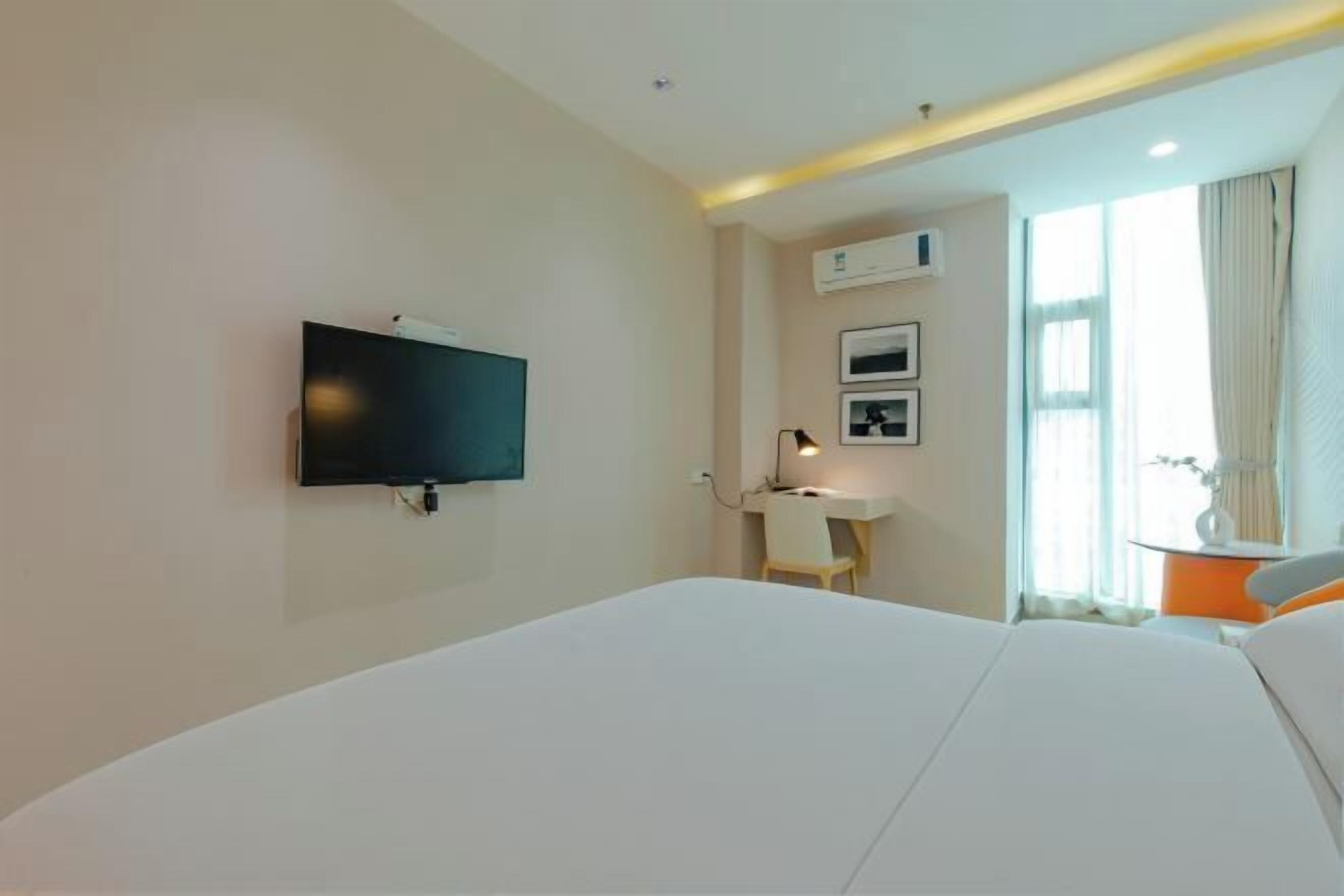 Habitación de hotel con una cama grande, un escritorio, un televisor de pantalla plana y una ventana con cortinas.