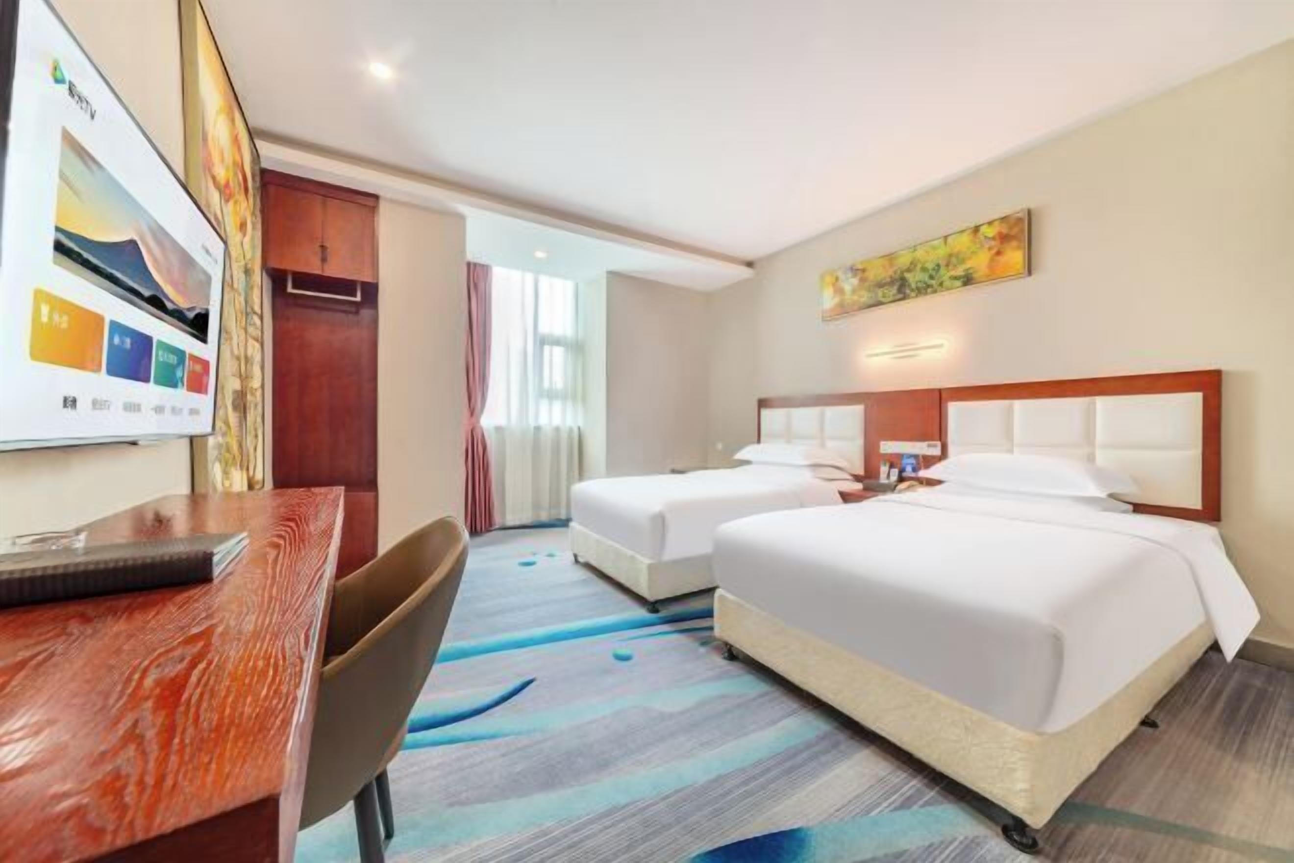 Habitación de hotel con dos camas, un escritorio y una silla.