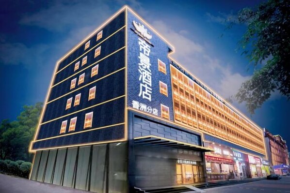 A multi-story hotel with a prominent sign, a covered entrance, and a row of shops at the ground level. - Dijing Wanyue Hotel (Zhuhai)