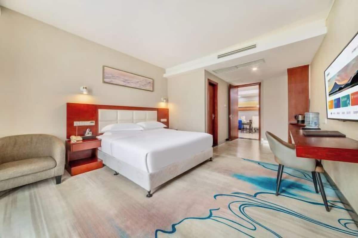 A hotel room with a bed, a desk, a chair, and a sofa.