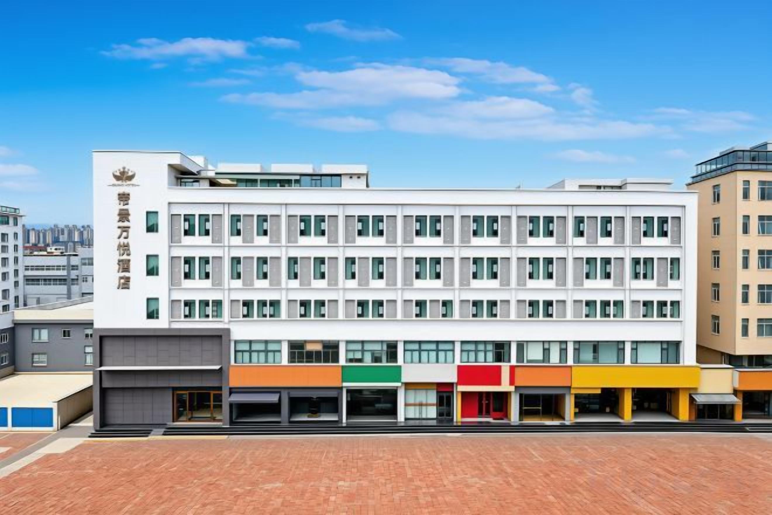 Ein mehrgeschossiges Hotel mit schlichter Fassade, zahlreichen Fenstern und einem Parkplatz davor.