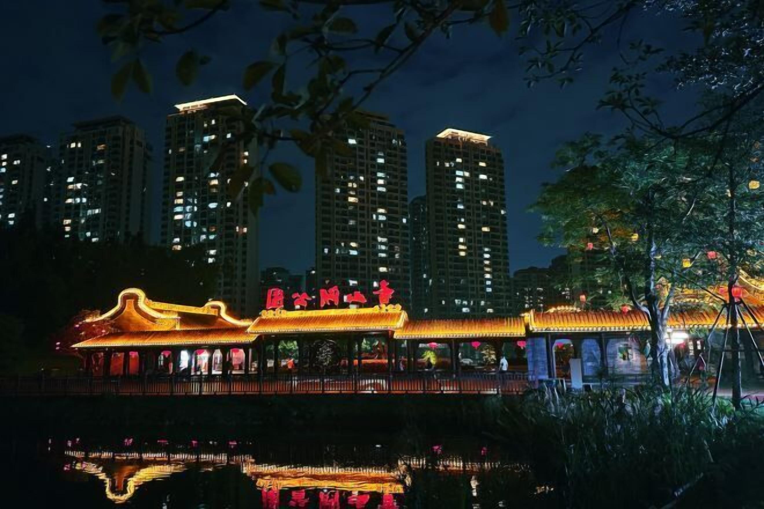 A traditional building with a reflection in the water, surrounded by modern high-rise buildings.