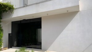 Un edificio moderno con una entrada amplia y abierta, un camino de hormigón y plantas verdes a lo largo del sendero.