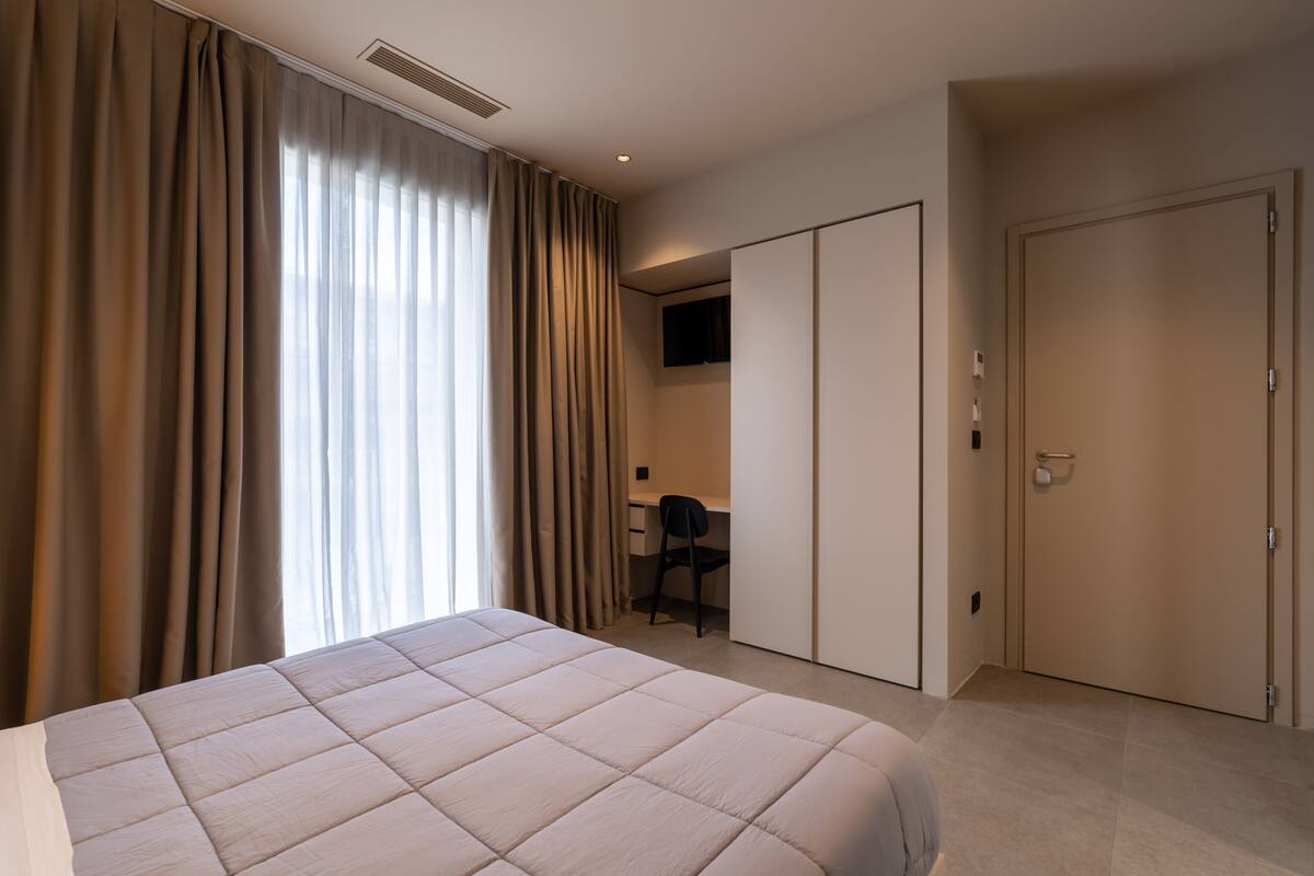 Ein Hotelzimmer mit einem großen Bett, einem Schreibtisch, einem Stuhl und einem Fernseher.