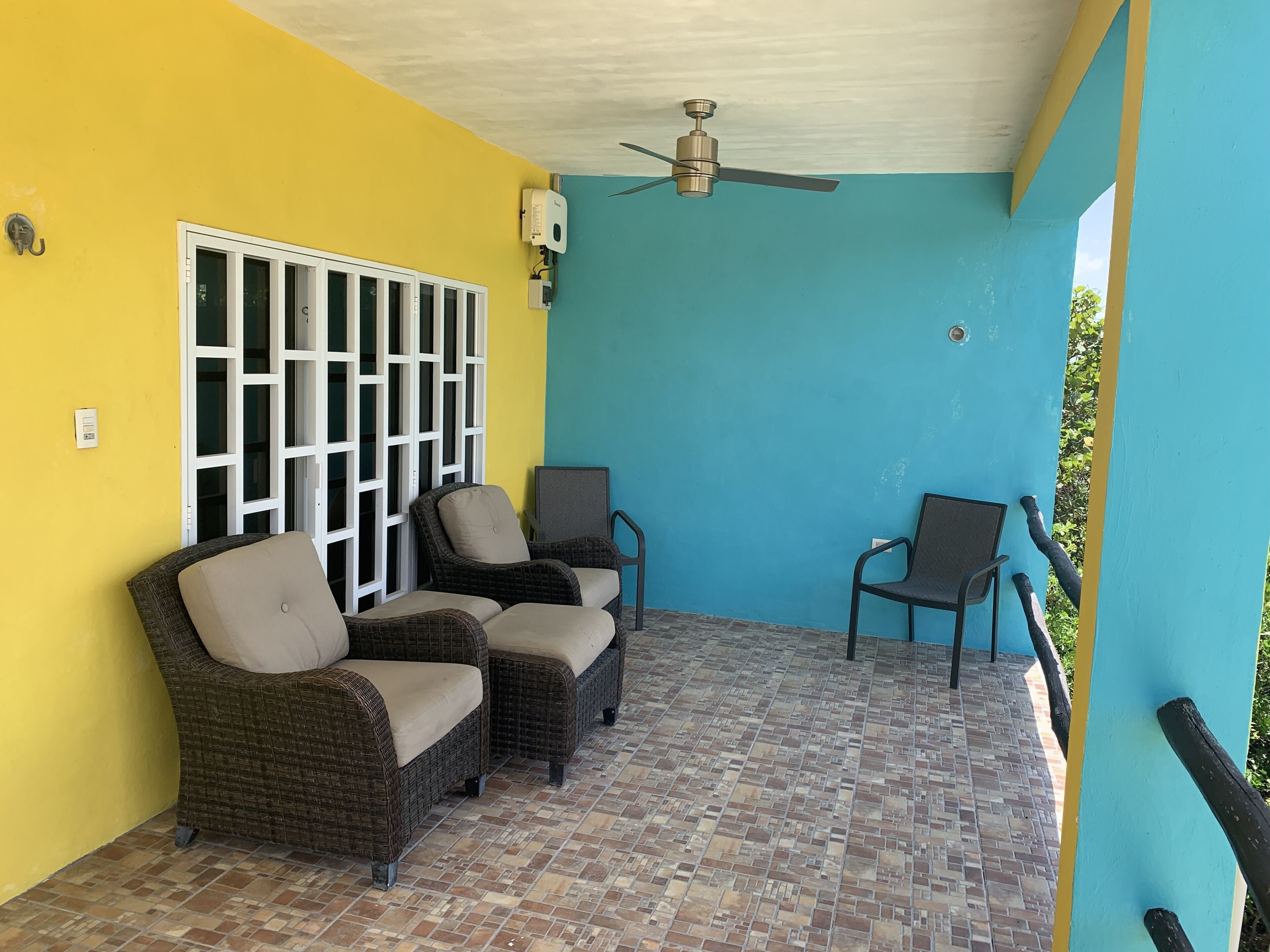 A covered patio with wicker furniture, a ceiling fan, and a view of the outside.