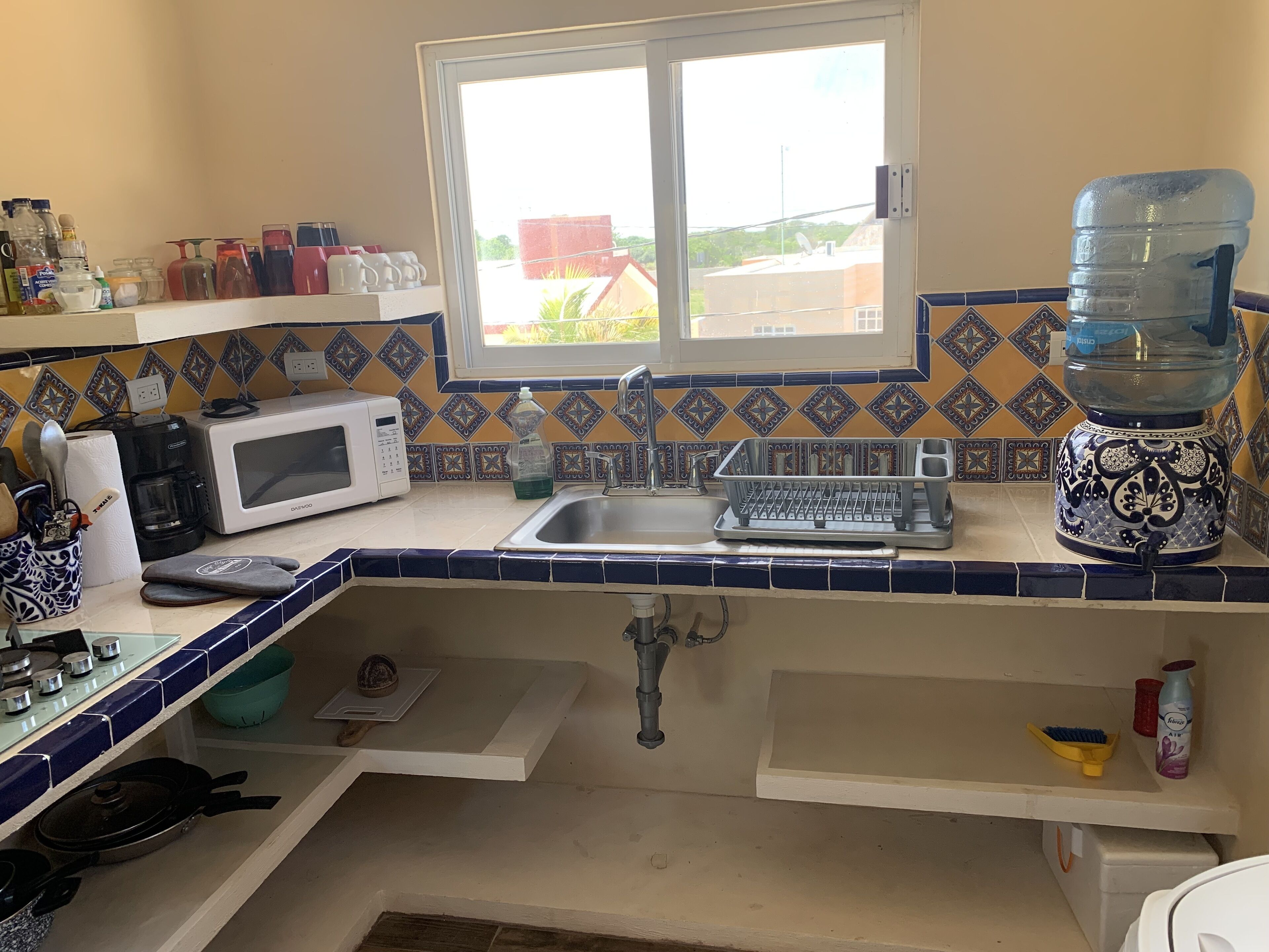 Cozinha equipada com micro-ondas, cafeteira, pia e janela.