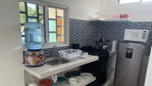 A compact kitchen with a sink, a water dispenser, a microwave, and a refrigerator.