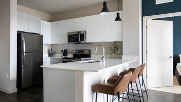 A modern kitchen with white cabinets, stainless steel appliances, and a central island with bar stools.
