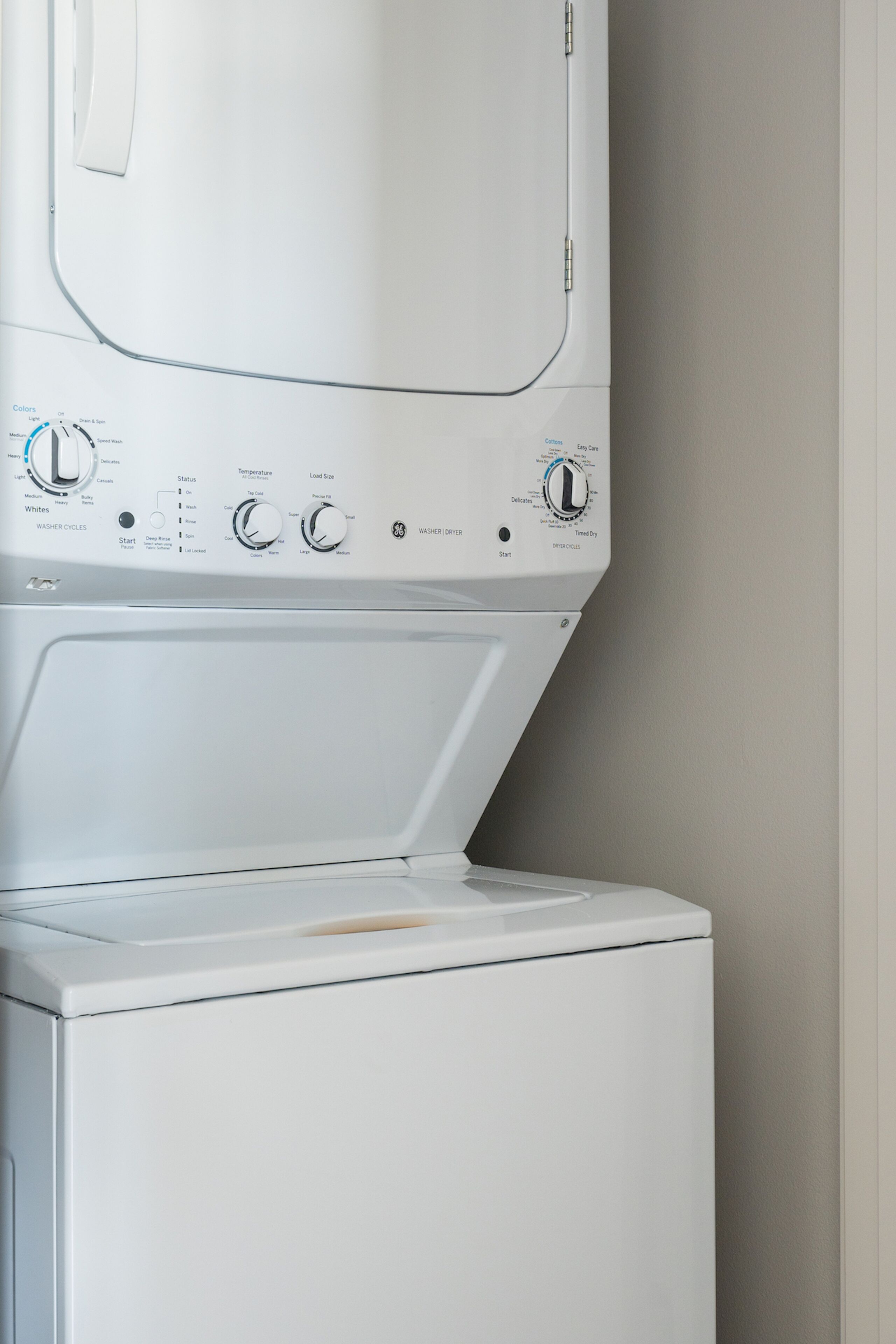 A front view of a white washing machine with control knobs and a digital display.