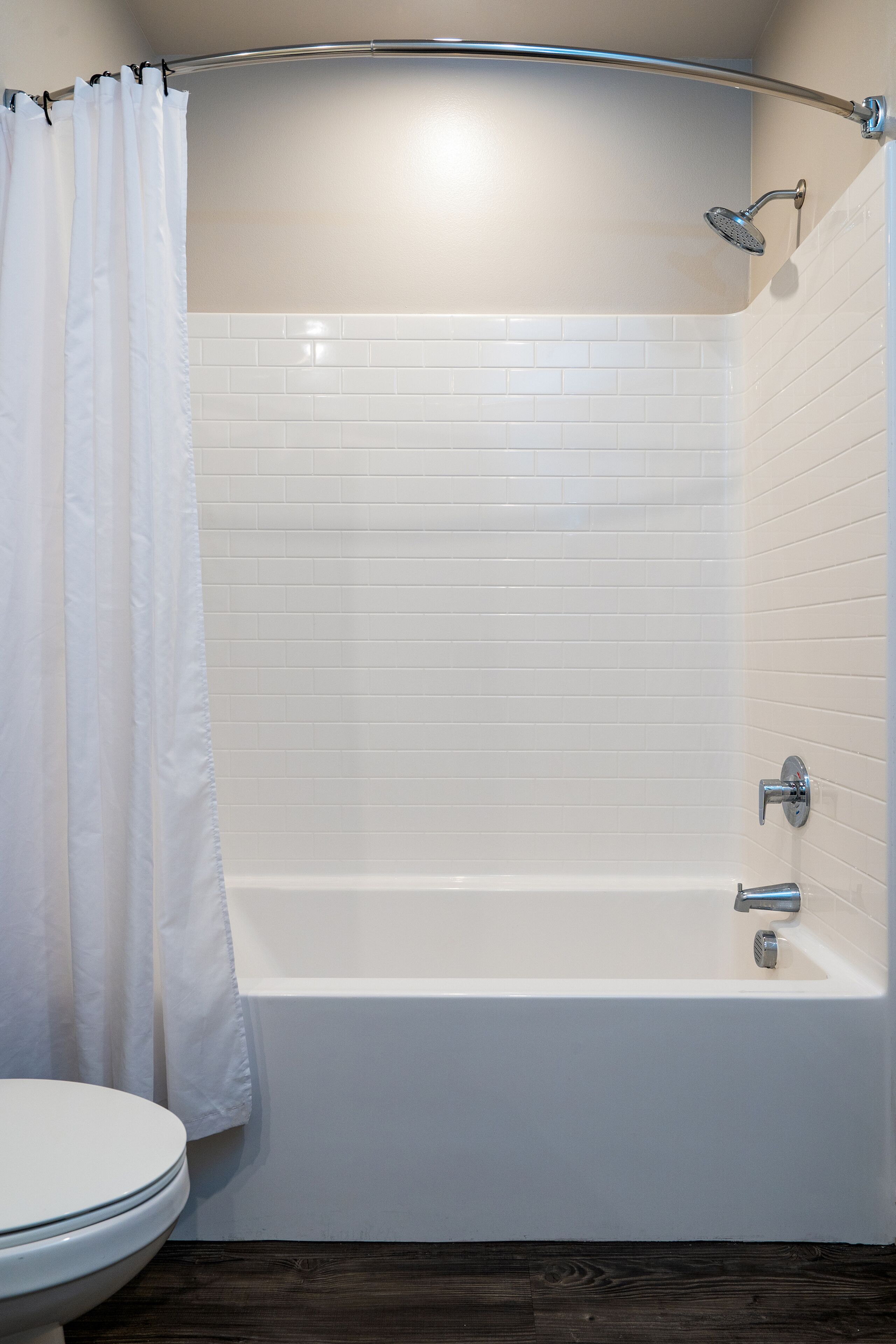 Un bagno con una vasca da bagno bianca, una doccetta e il water.