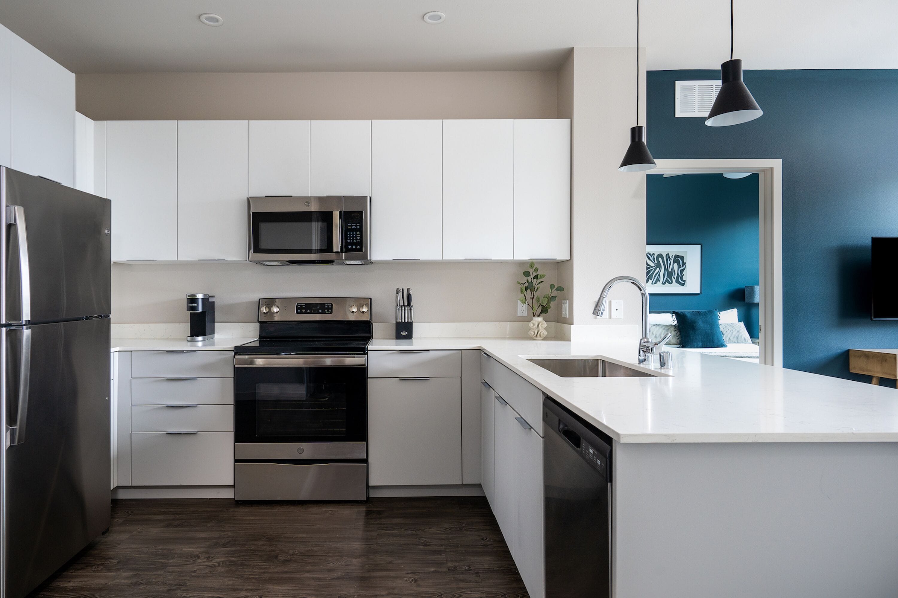 Une cuisine moderne dotée d’appareils électroménagers en acier inoxydable, de meubles blancs et d’un mur d’accent bleu.