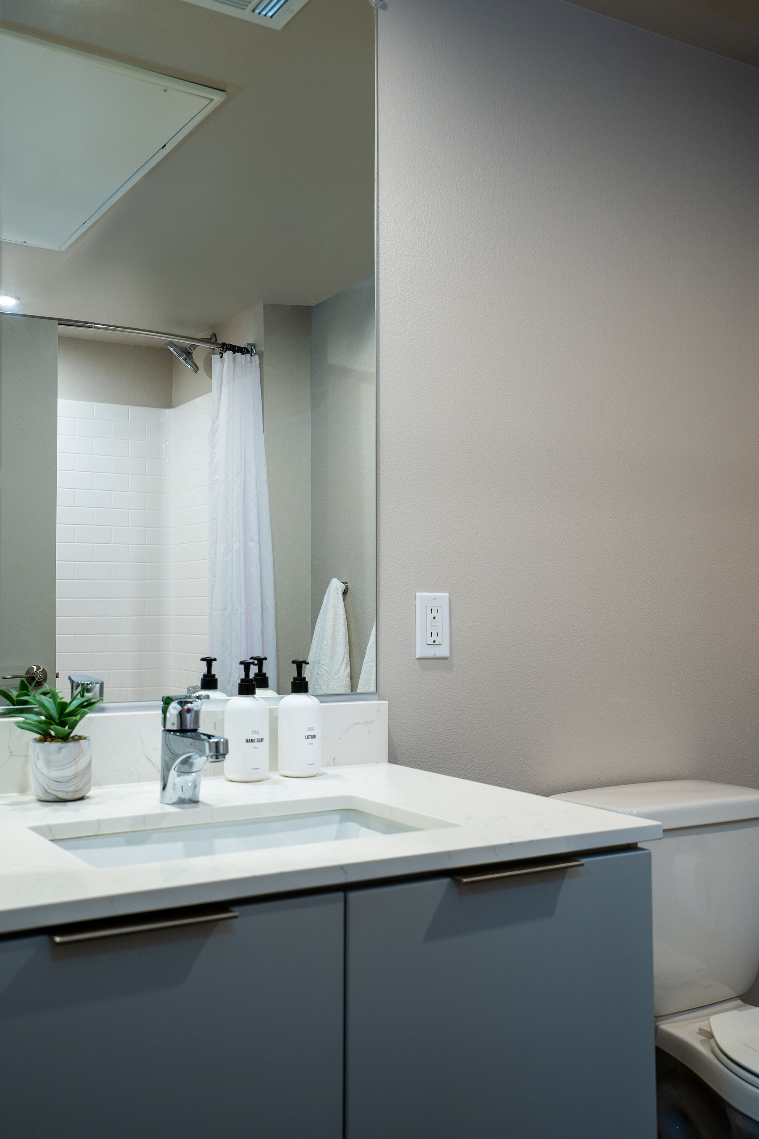 Un baño moderno con un lavamanos blanco, un espejo y una cortina de ducha.