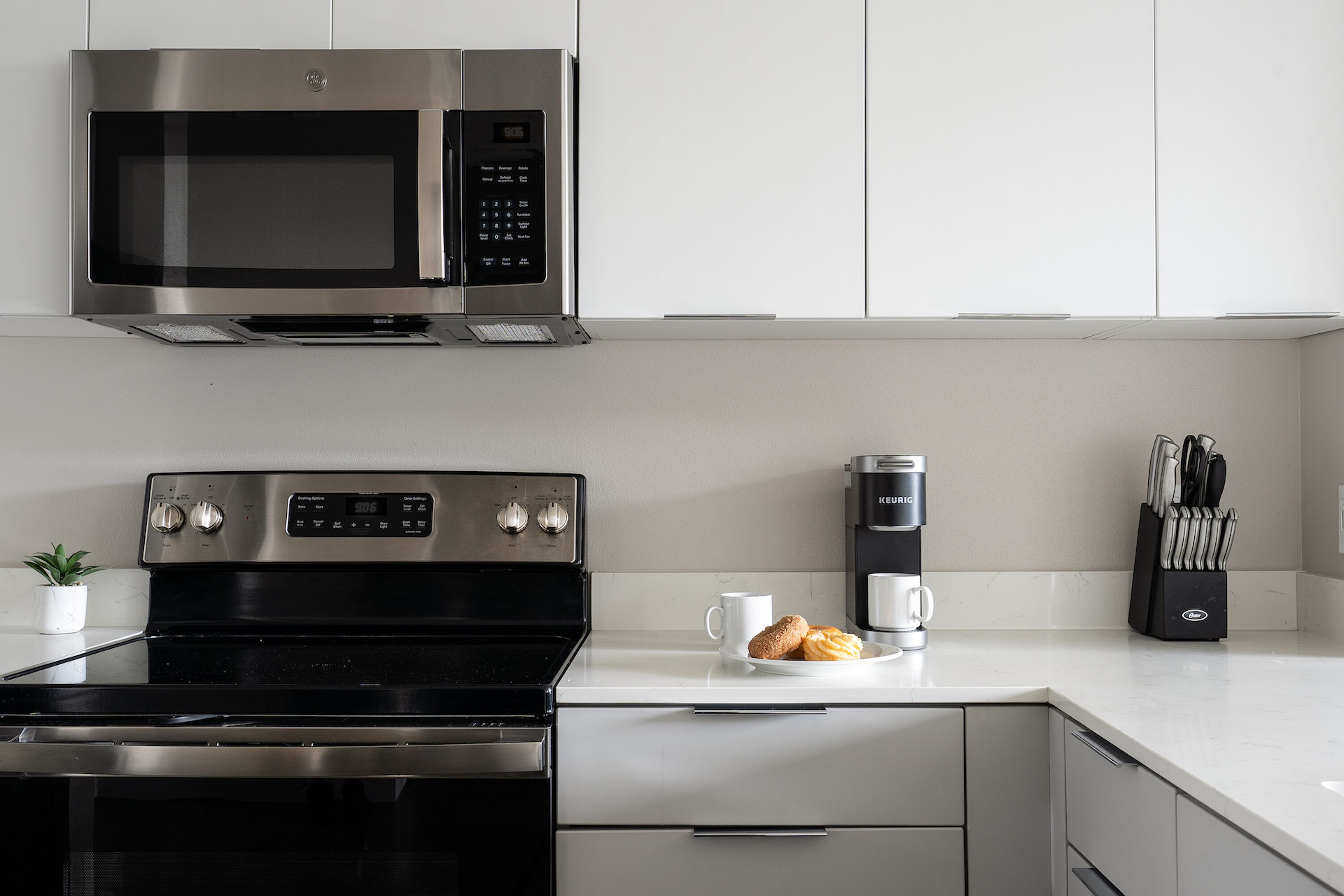 A modern kitchen with a stainless steel microwave, stove, and coffee maker.