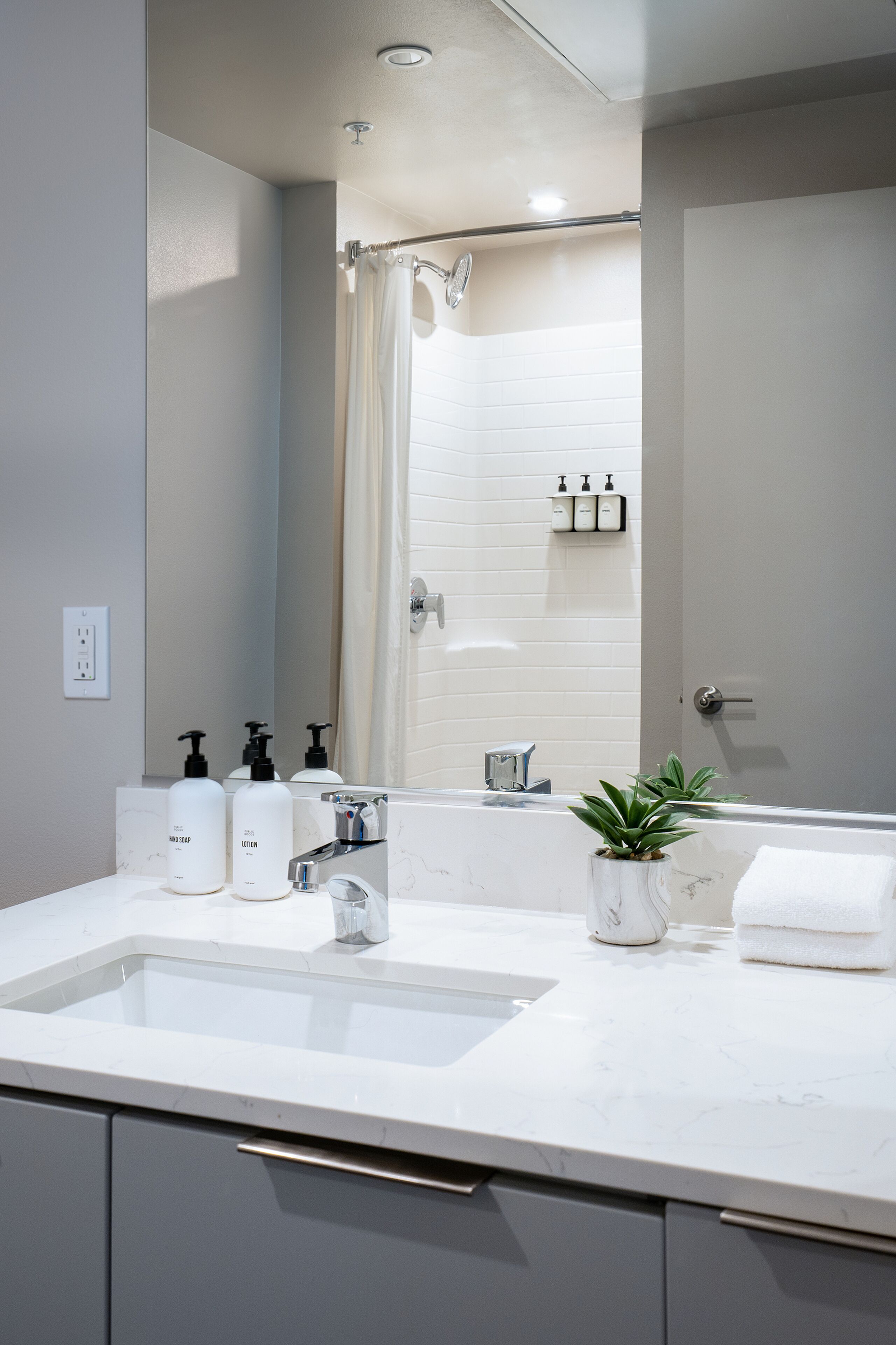 Un baño moderno con un lavabo grande, un espejo y una cortina de ducha.