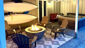 A covered outdoor seating area with a fire pit, chairs, and a hot tub. - Dog-Friendly Cottage with hot tub, kayaks, e-bike (Eastsound)
