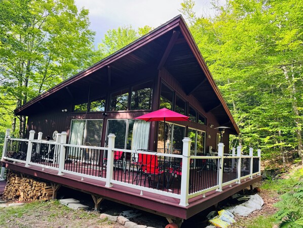 A cabin with a covered deck, large windows, and a red umbrella.