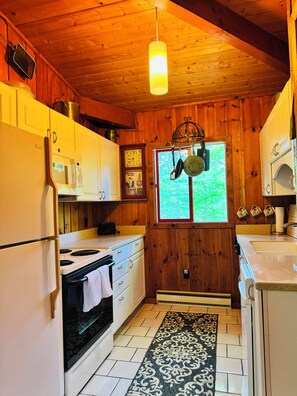 Une cuisine avec des murs en bois, un four à micro-ondes, une cuisinière et un porte-ustensiles suspendu.