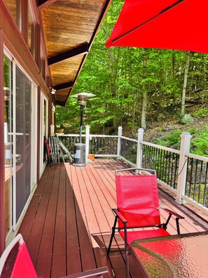 A wooden deck with a red umbrella, a chair, and a lantern. - Family size Cabin w deck, Resort Pool &Spa walk to gondola & Scottish Festival  (Lincoln)