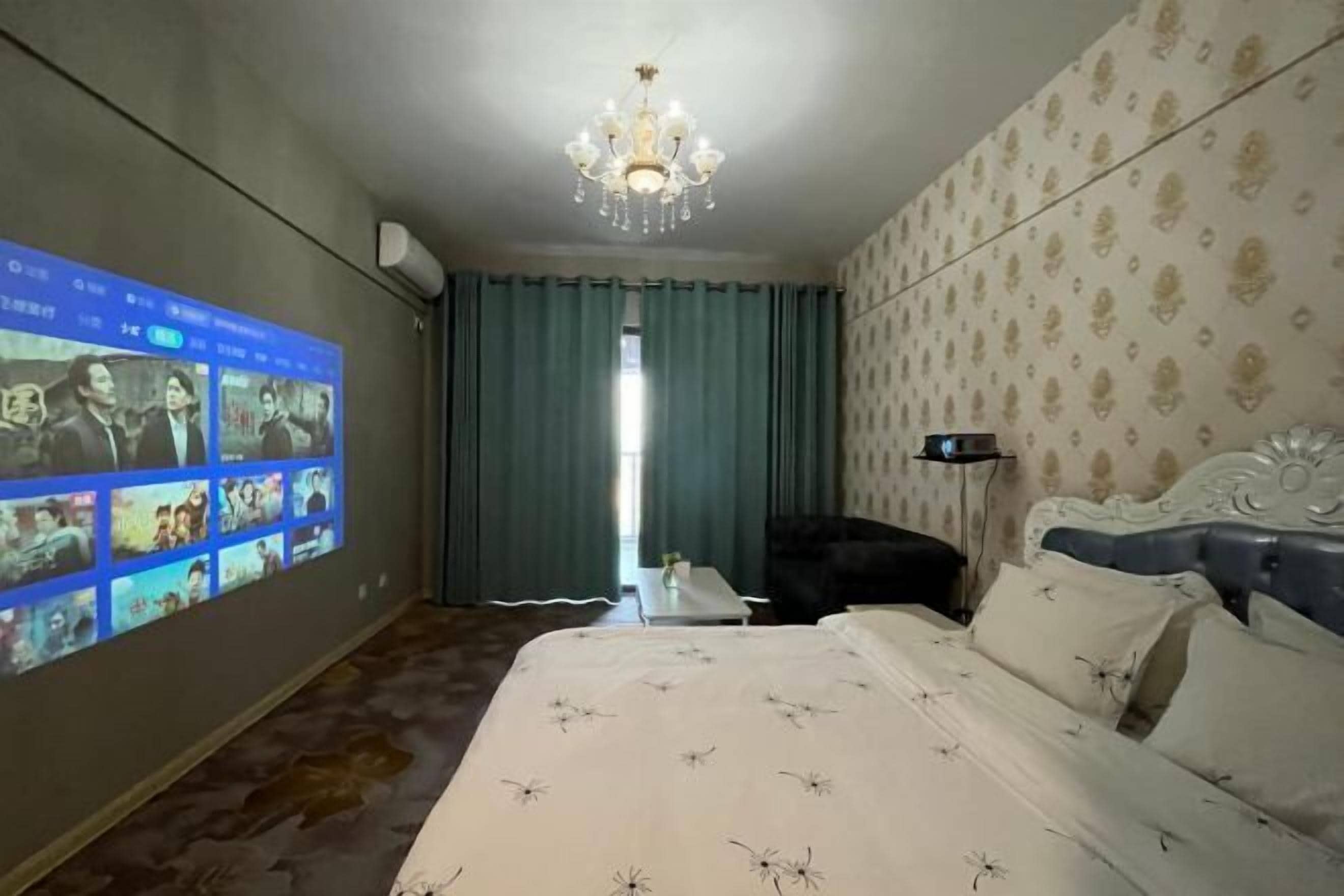 Una habitación de hotel con cama, lámpara de araña, televisor mostrando contenido, escritorio y silla.