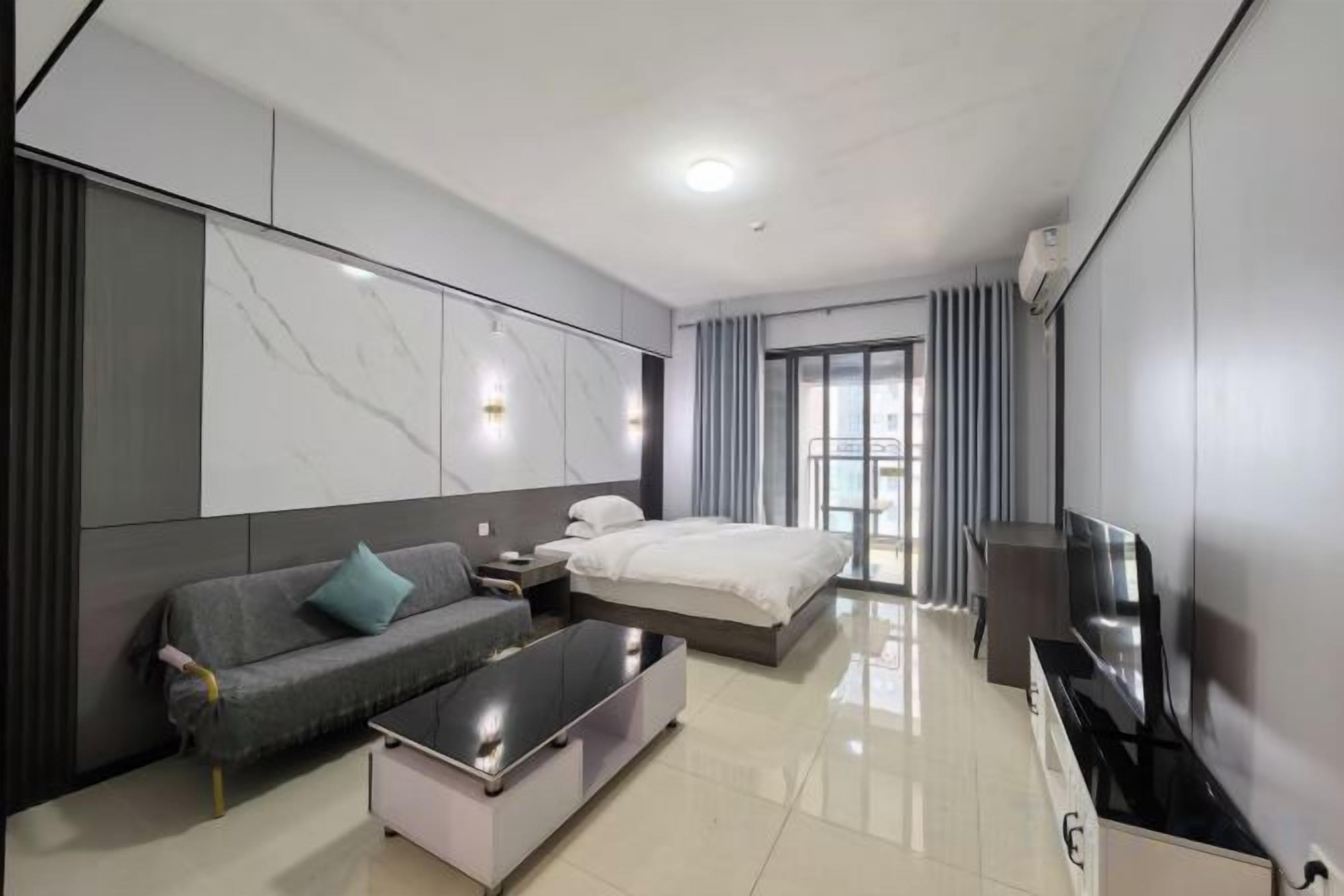 Une chambre d’hôtel moderne équipée d’un lit, d’un canapé, d’un téléviseur et d’un téléviseur à écran plat posé sur un meuble.
