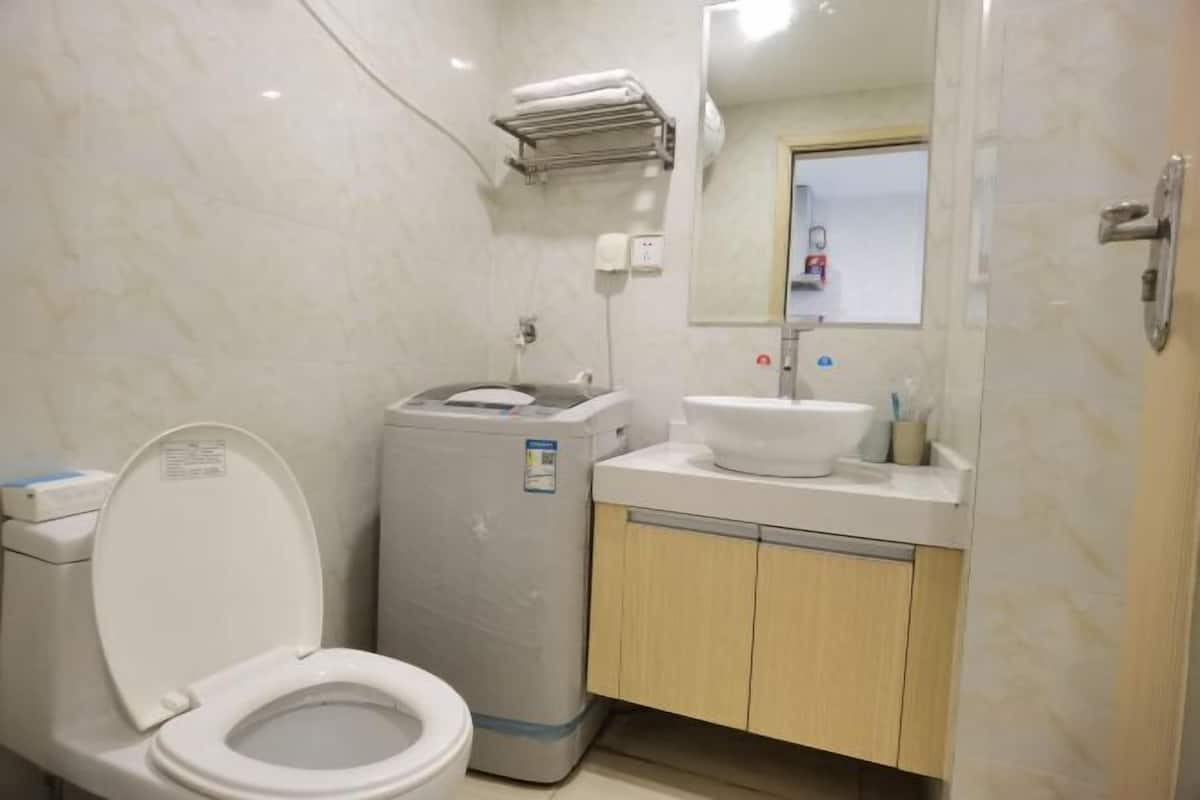 Une petite salle de bain comprenant des toilettes, un lave-linge, un lavabo et un miroir.